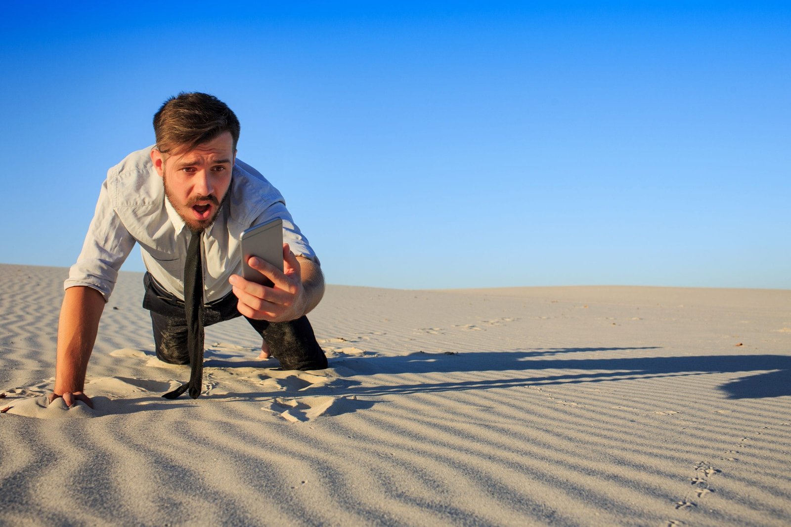 Poor signal. businessman searching for mobile phone signal in desert